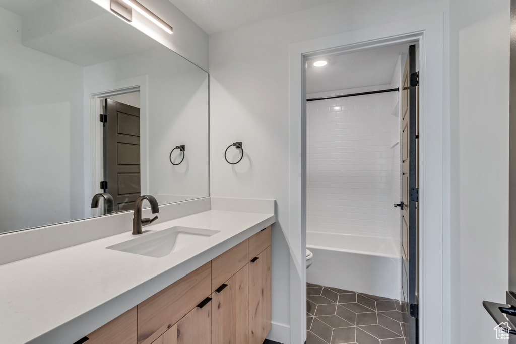 Full bathroom with tiled shower / bath, vanity, toilet, and tile patterned floors