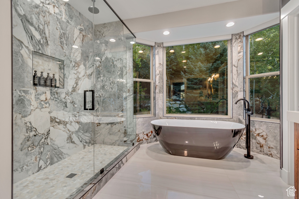 Bathroom featuring shower with separate bathtub, tile walls, and tile patterned floors