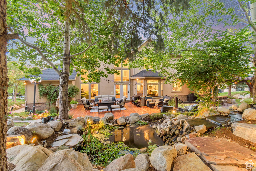 Back house at dusk featuring an outdoor hangout area and a deck