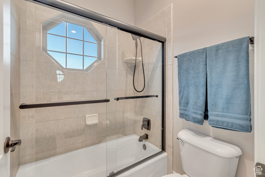 Bathroom with shower / bath combination with glass door and toilet