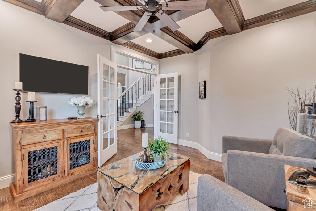 Living room with coffered ceiling, beamed ceiling, crown molding, ceiling fan, and hardwood / wood-style floors