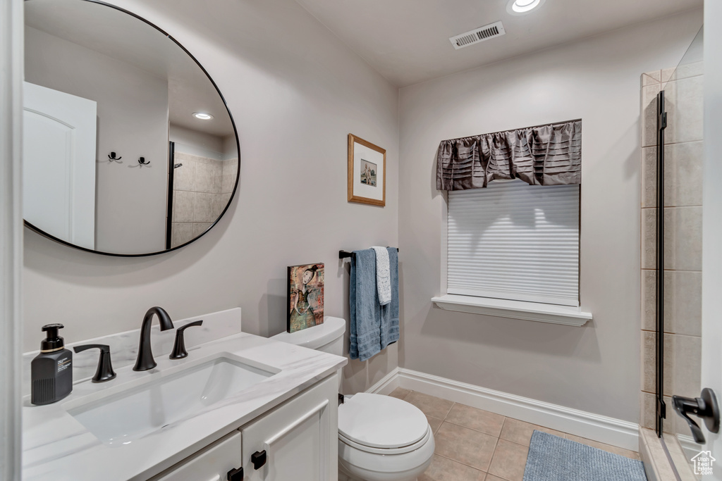 Bathroom featuring tile patterned floors, walk in shower, vanity, and toilet