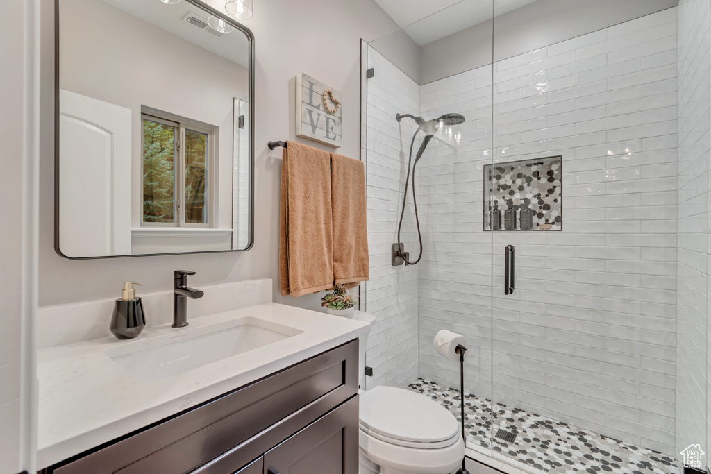 Bathroom featuring vanity, a shower with shower door, and toilet