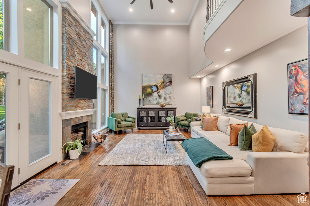 Living room with ceiling fan, a fireplace, and a towering ceiling