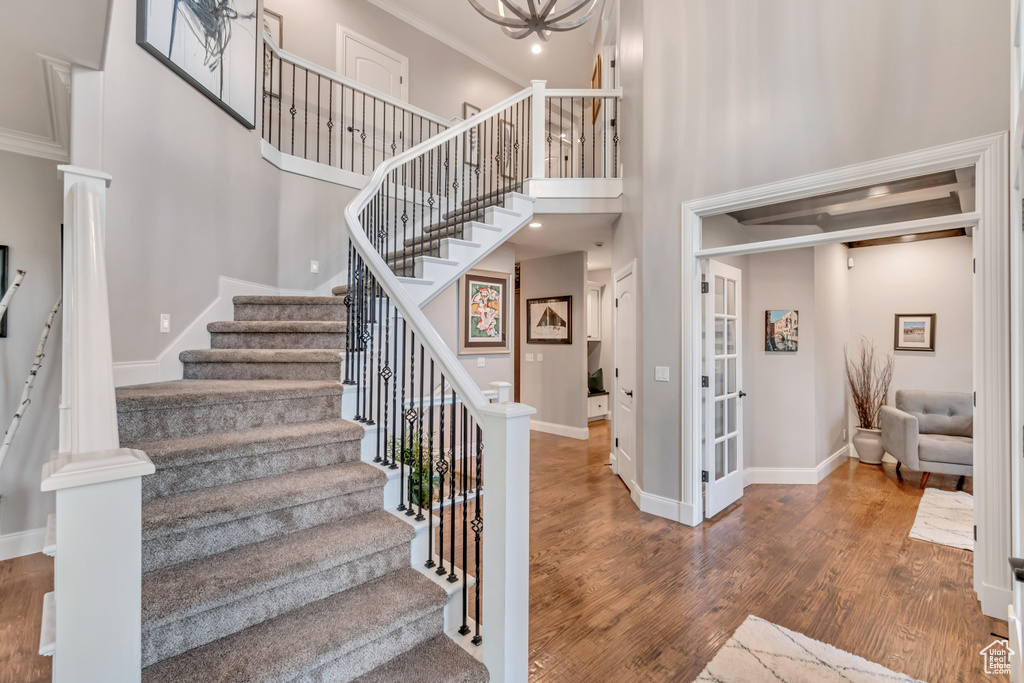 Stairs with wood-type flooring, crown molding, and a high ceiling