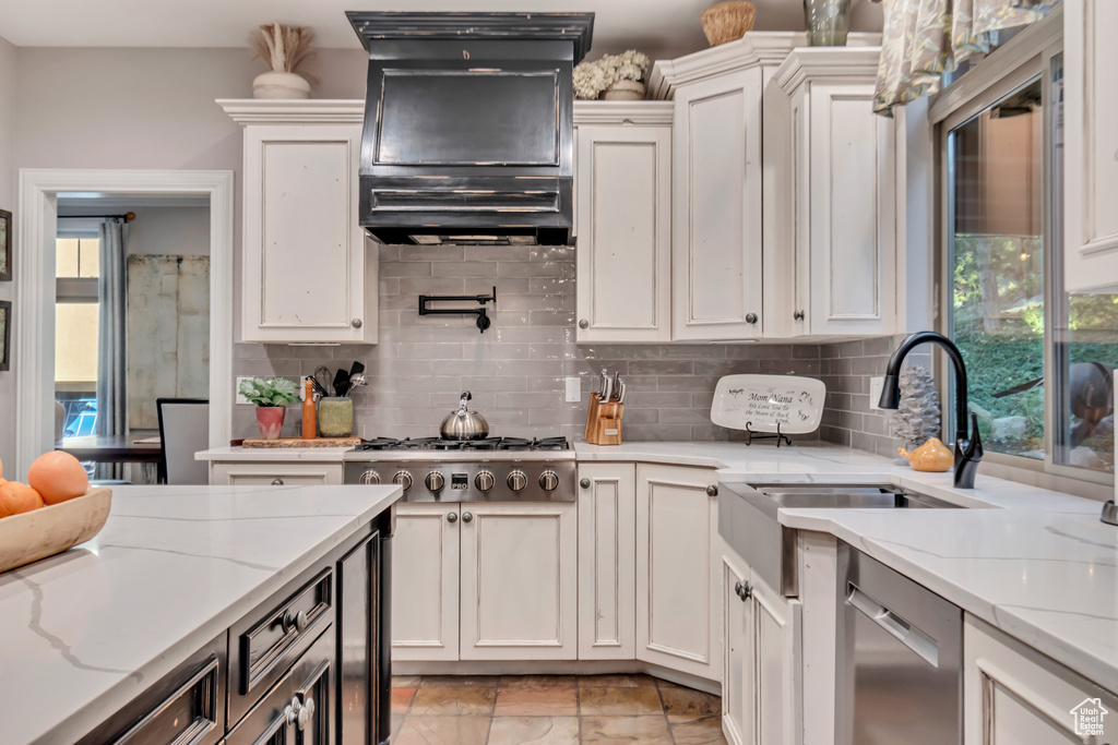 Kitchen featuring light stone counters, stainless steel appliances, sink, and a wealth of natural light