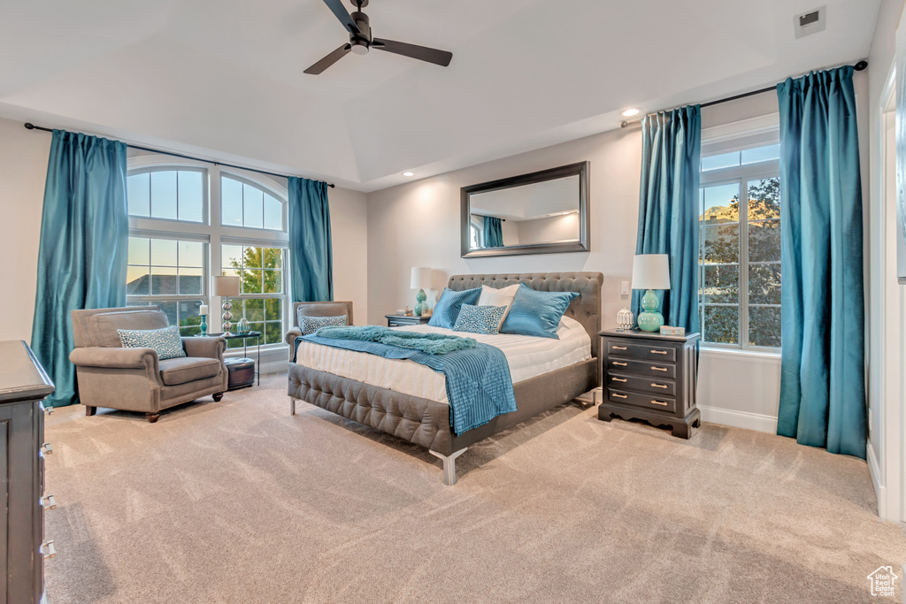 Carpeted bedroom featuring multiple windows and ceiling fan