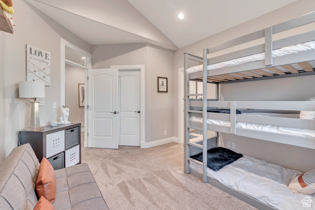 Bedroom featuring light carpet and vaulted ceiling