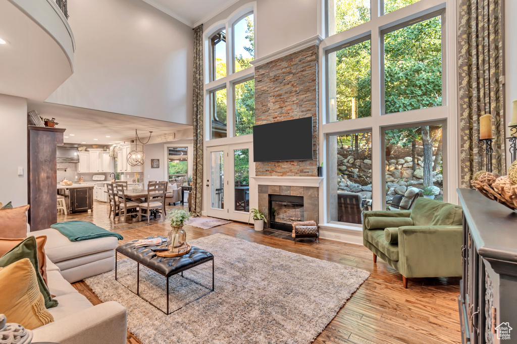 Living room featuring crown molding, light hardwood / wood-style floors, a towering ceiling, and plenty of natural light