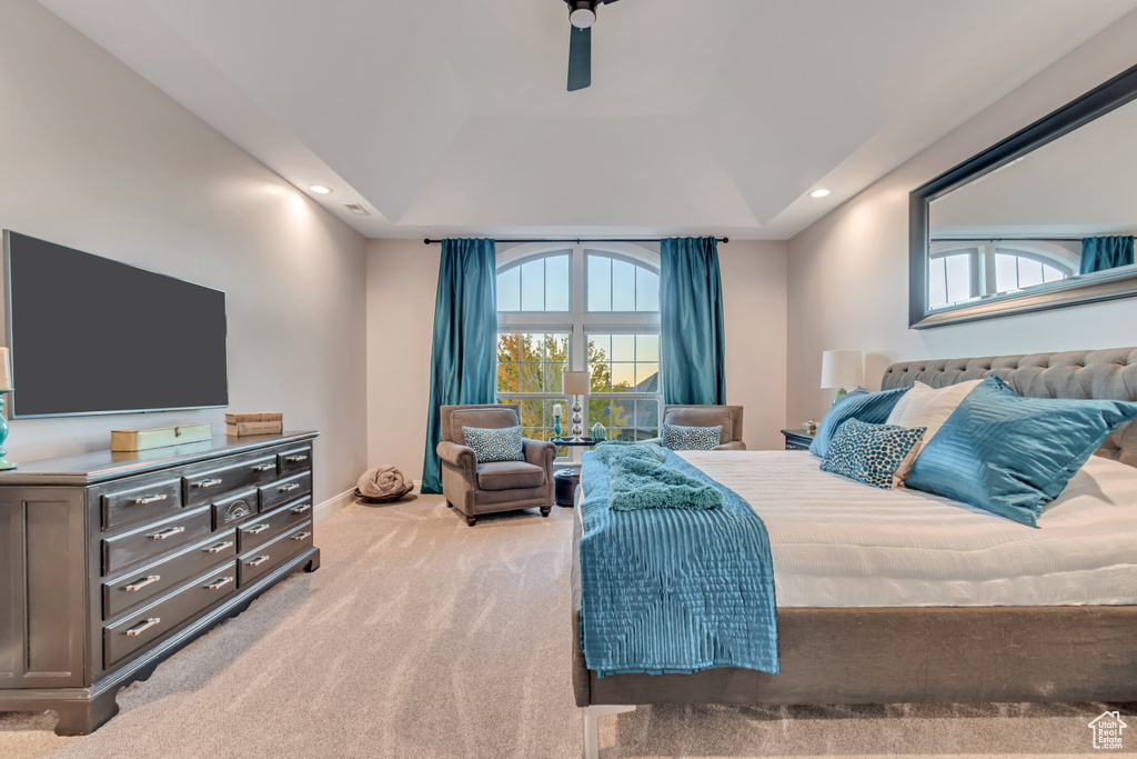 Carpeted bedroom with a raised ceiling and ceiling fan