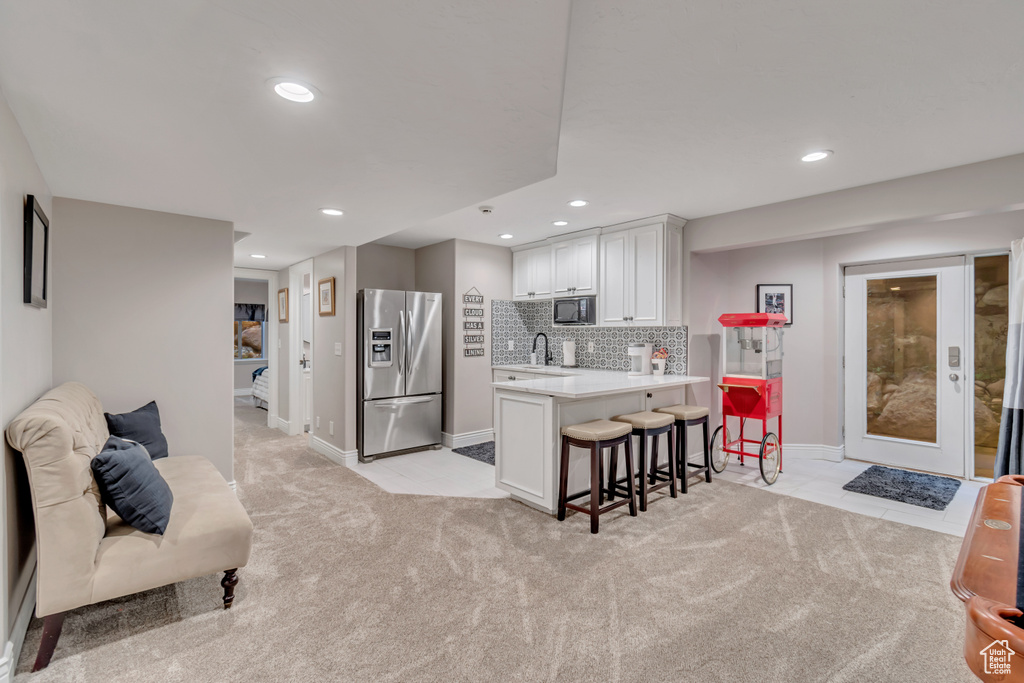 Kitchen with stainless steel fridge with ice dispenser, tasteful backsplash, white cabinets, a kitchen breakfast bar, and built in microwave