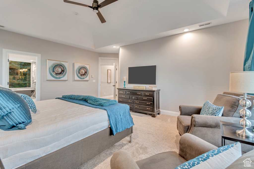 Bedroom featuring ceiling fan, light colored carpet, and ensuite bathroom