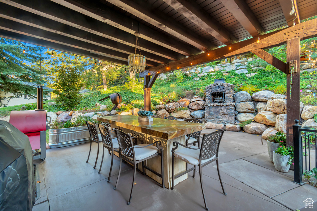 View of patio with area for grilling and a fireplace