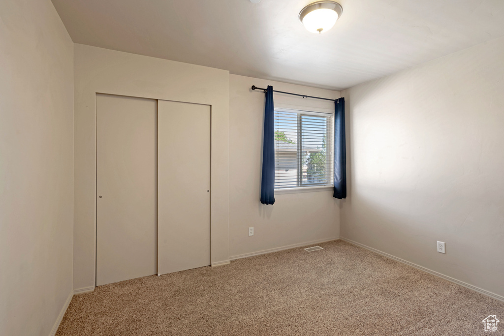 Unfurnished bedroom with light carpet and a closet