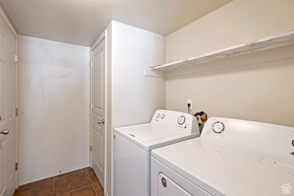 Clothes washing area featuring washer and clothes dryer and dark tile patterned flooring