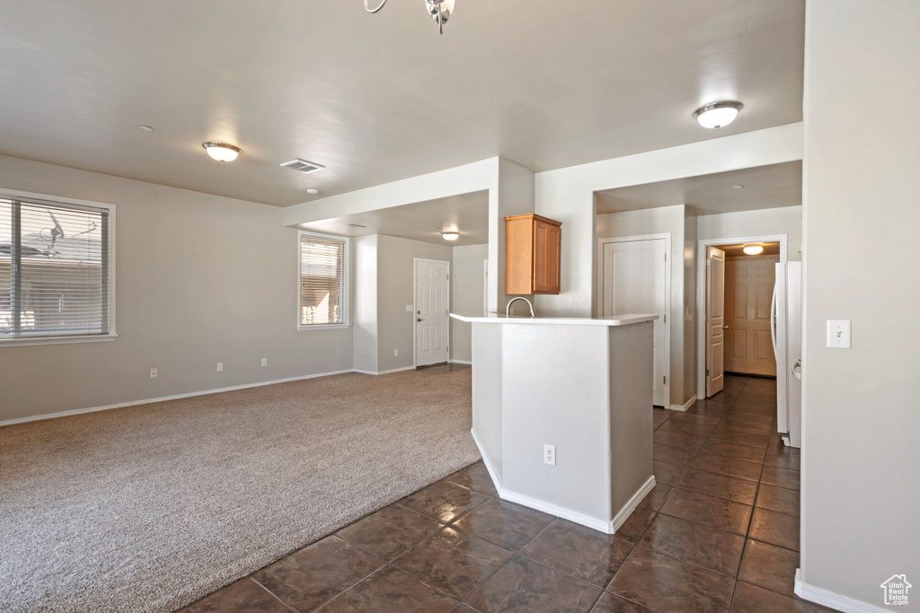 Kitchen with dark colored carpet, plenty of natural light, white fridge, and kitchen peninsula