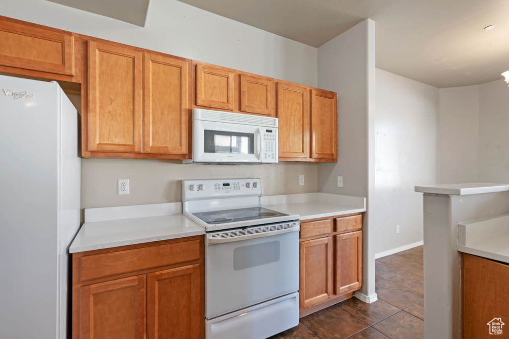 Kitchen with dark tile patterned flooring and white appliances