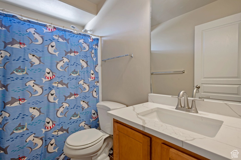 Bathroom with vanity, toilet, and curtained shower