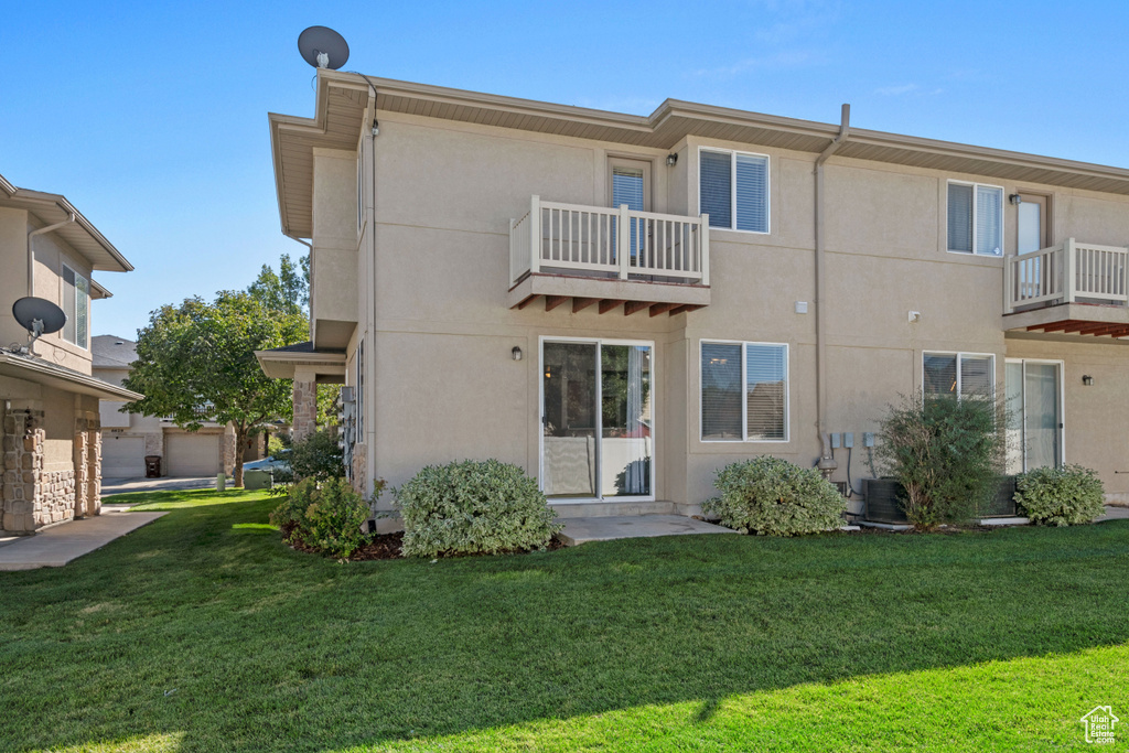 Back of house with a balcony and a lawn