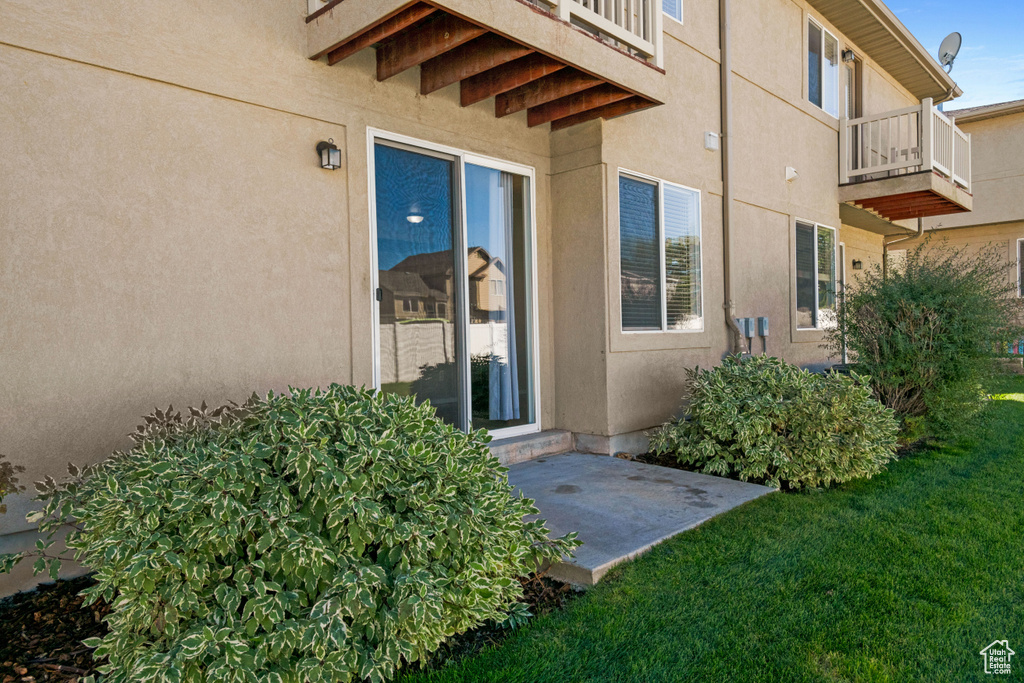 Entrance to property featuring a lawn, a balcony, and a patio