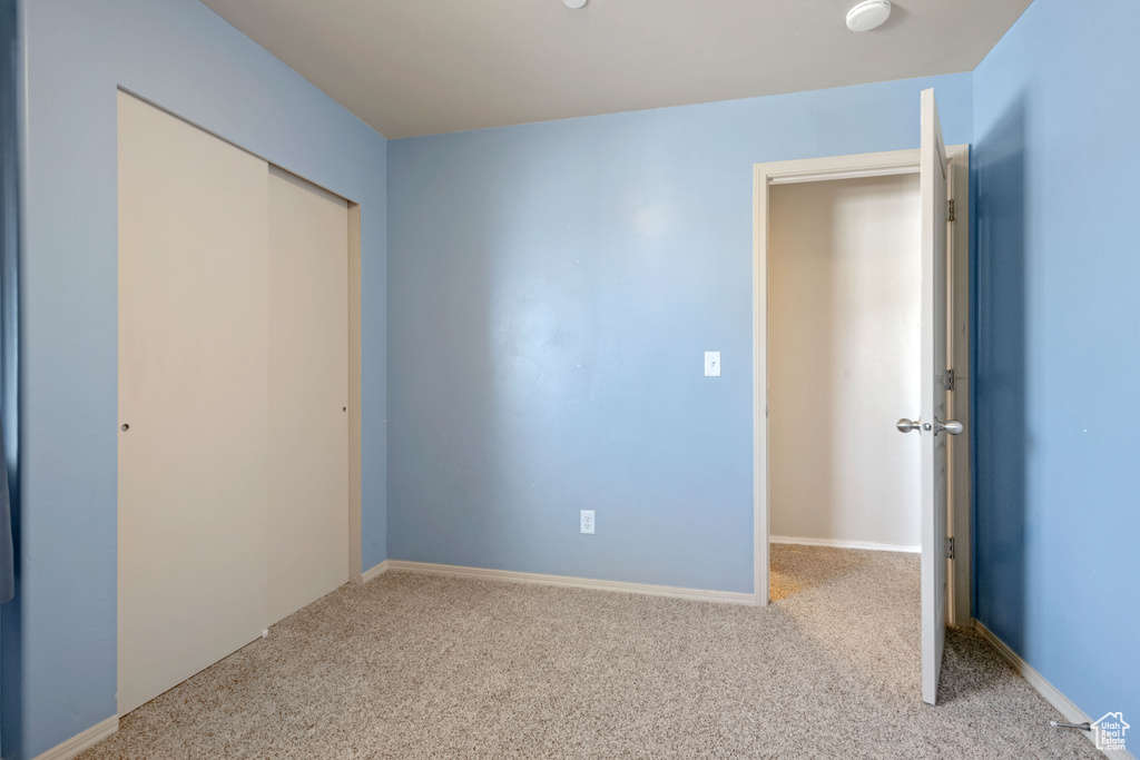 Unfurnished bedroom with light colored carpet and a closet