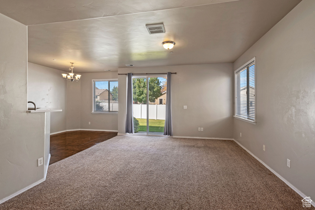 Carpeted empty room featuring an inviting chandelier