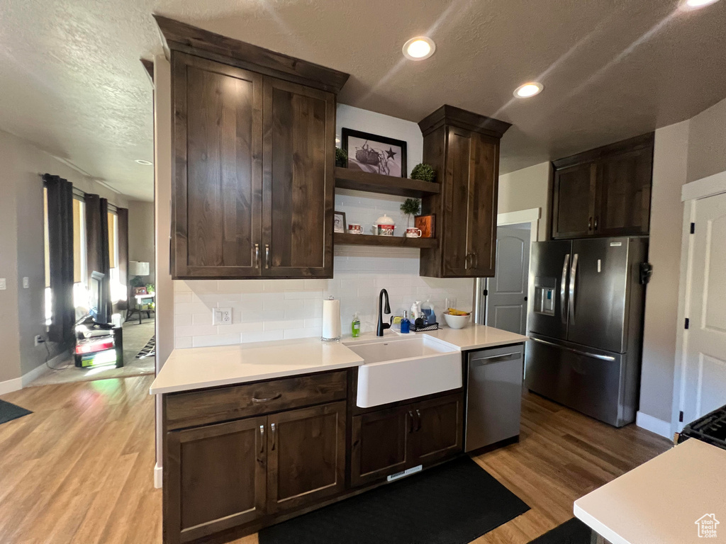 Kitchen with decorative backsplash, sink, light hardwood / wood-style flooring, and stainless steel appliances