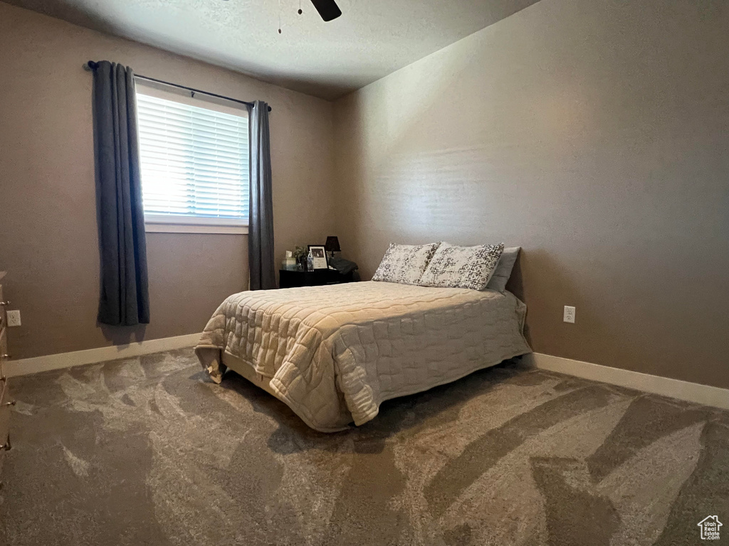 Carpeted bedroom featuring ceiling fan and a textured ceiling