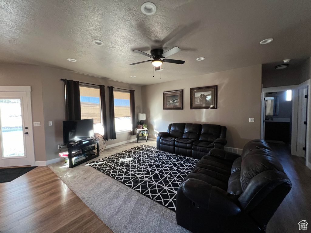 Living room with ceiling fan, plenty of natural light, hardwood / wood-style floors, and a textured ceiling