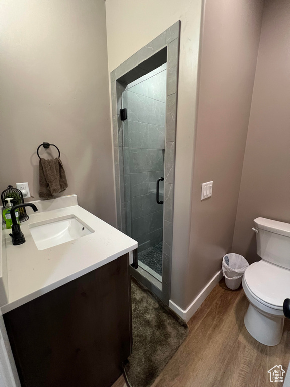 Bathroom with hardwood / wood-style flooring, vanity, toilet, and a shower with door