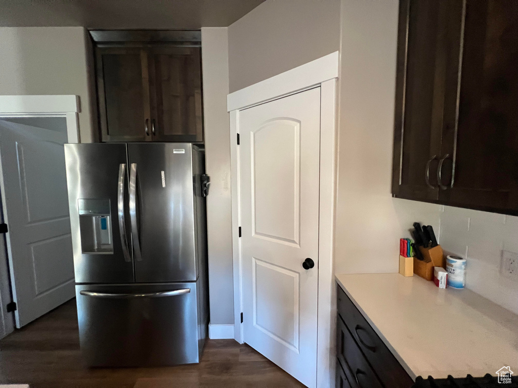 Kitchen with stainless steel refrigerator with ice dispenser, dark brown cabinetry, and dark hardwood / wood-style flooring