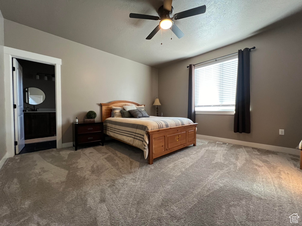 Carpeted bedroom with ceiling fan, a textured ceiling, and connected bathroom