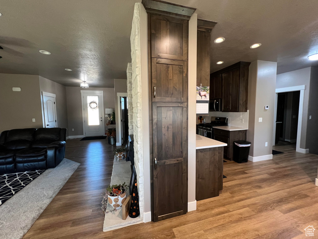 Kitchen with light hardwood / wood-style flooring, stainless steel appliances, a textured ceiling, and dark brown cabinets