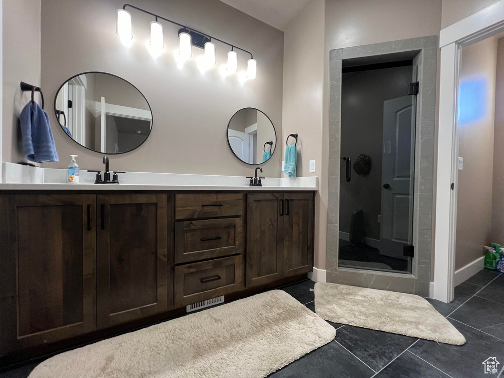 Bathroom with tile patterned flooring, vanity, and a shower with door