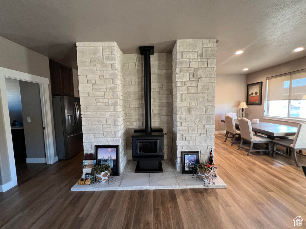 Living room featuring a textured ceiling, a wood stove, and hardwood / wood-style flooring