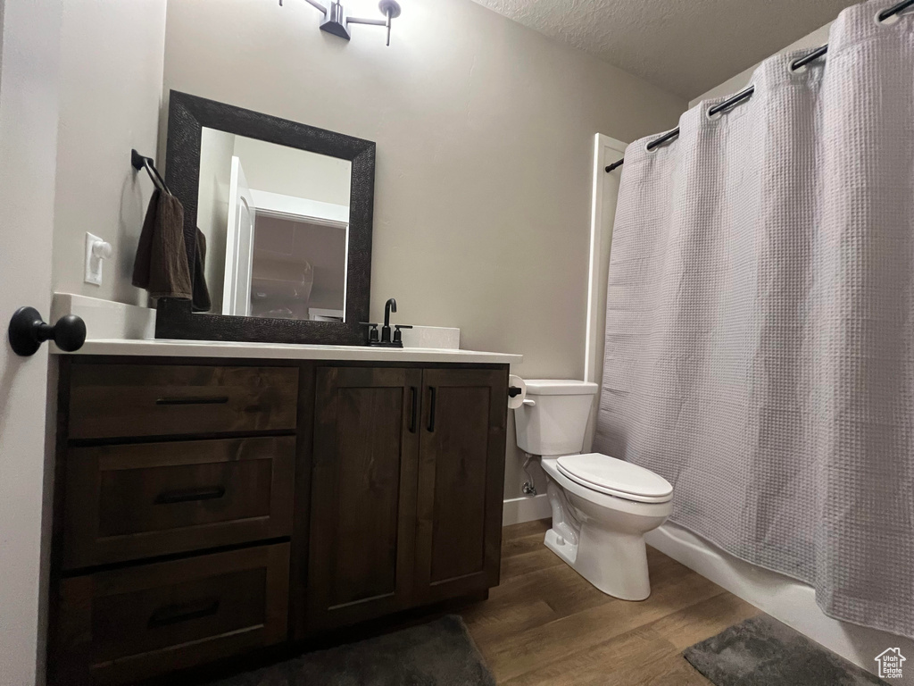 Full bathroom with a textured ceiling, hardwood / wood-style flooring, vanity, and toilet