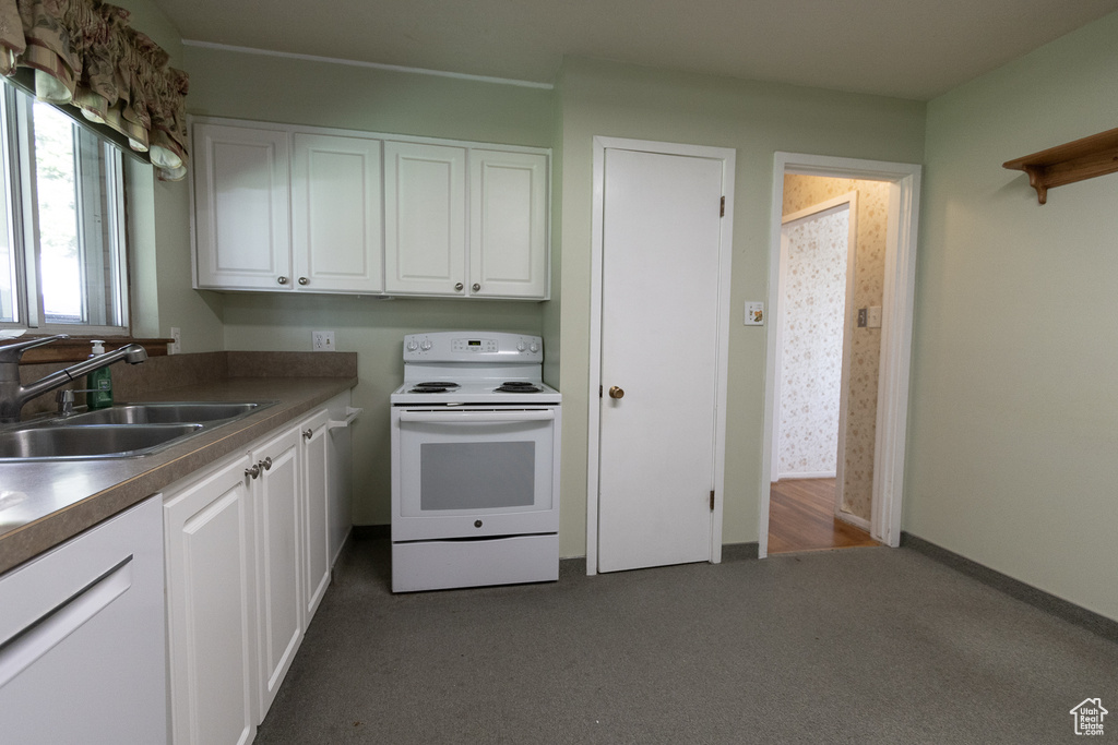 Kitchen featuring white cabinets, dark colored carpet, sink, and white appliances