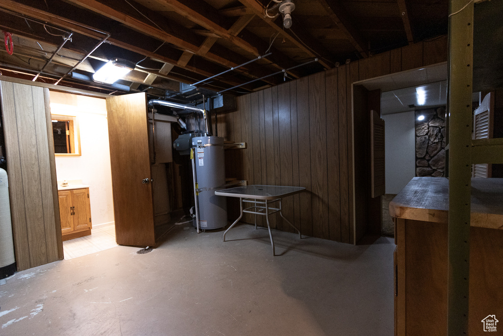 Basement with water heater and wood walls