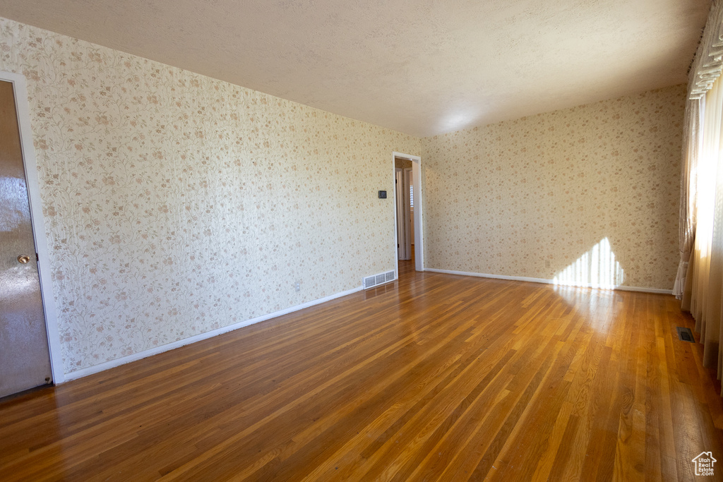 Empty room with a textured ceiling and dark hardwood / wood-style floors