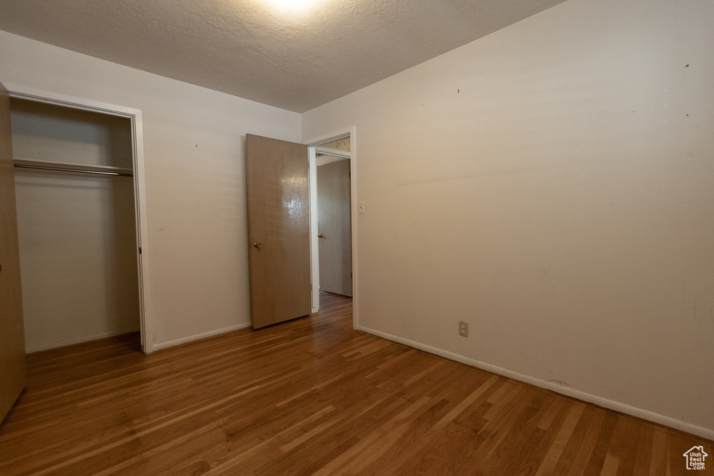 Unfurnished bedroom featuring wood-type flooring, a closet, and a textured ceiling