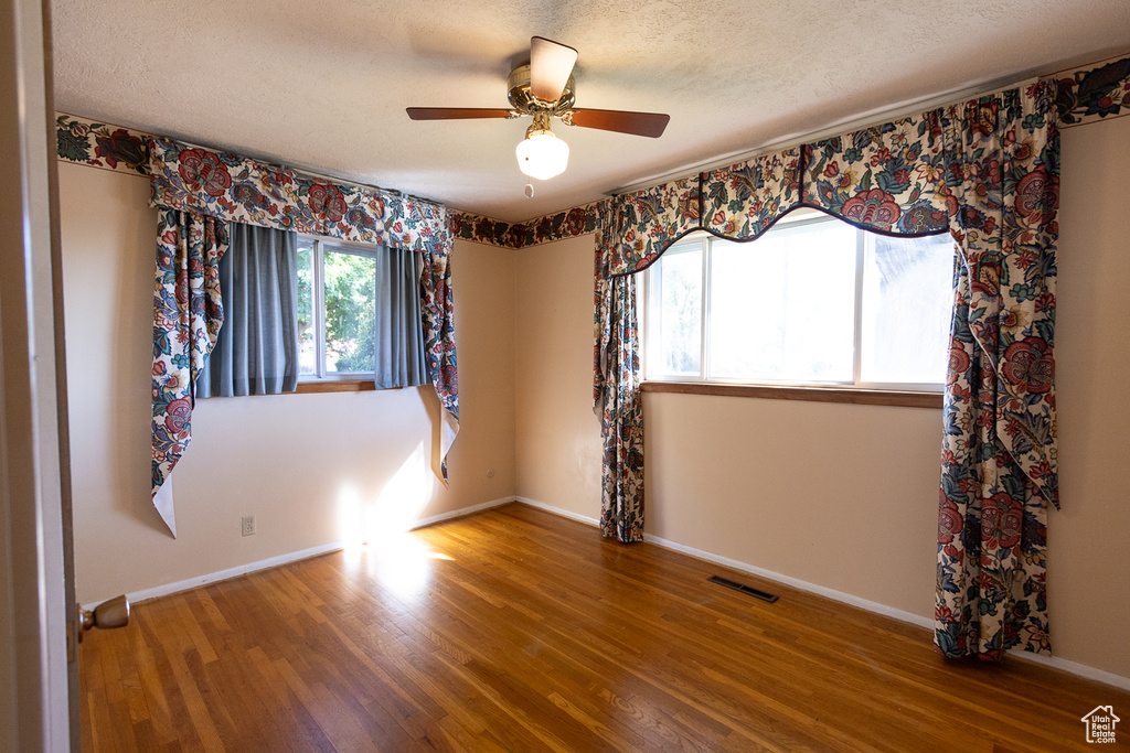 Unfurnished room with wood-type flooring, ceiling fan, and a textured ceiling