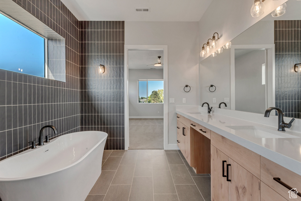 Bathroom with vanity, a tub to relax in, tile walls, and tile patterned floors