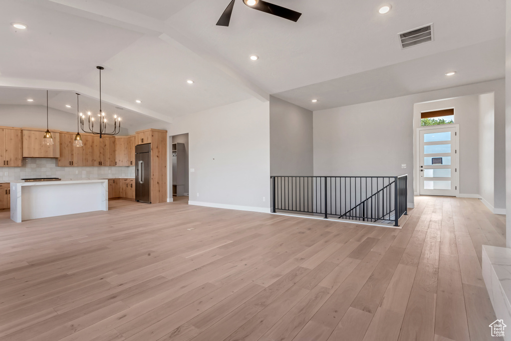 Kitchen featuring high end refrigerator, light hardwood / wood-style floors, lofted ceiling with beams, ceiling fan with notable chandelier, and pendant lighting