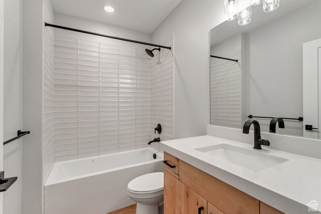 Full bathroom with tiled shower / bath combo, vanity, and toilet