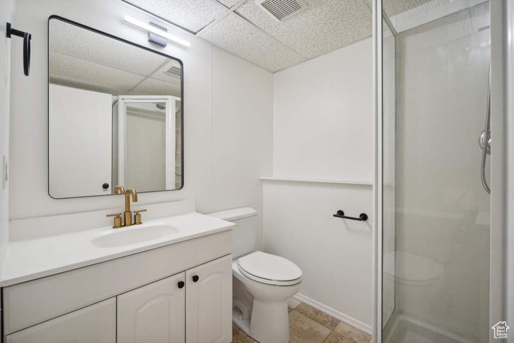 Bathroom featuring vanity, an enclosed shower, a paneled ceiling, toilet, and tile patterned floors