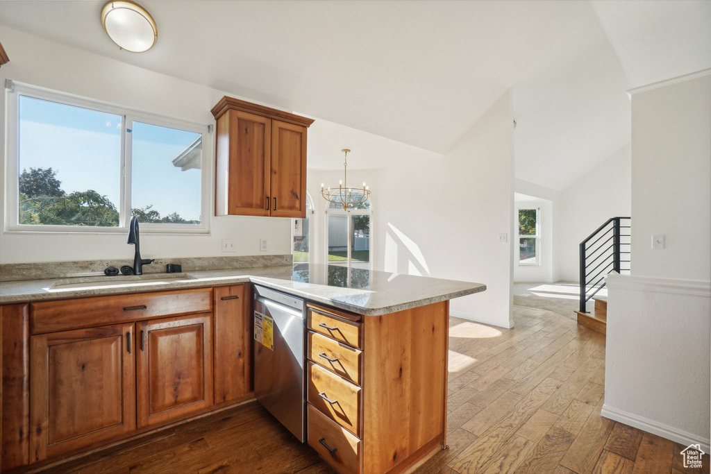 Kitchen with lofted ceiling, sink, kitchen peninsula, stainless steel dishwasher, and wood-type flooring