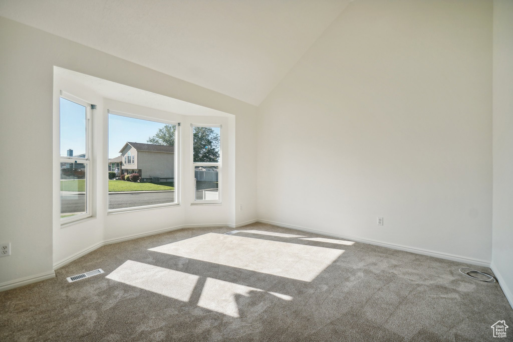 Carpeted empty room featuring lofted ceiling