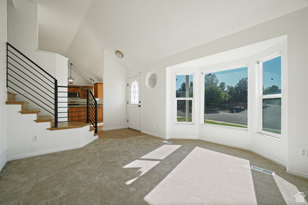 Foyer entrance with carpet and lofted ceiling