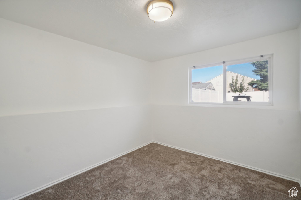 Empty room with vaulted ceiling and carpet floors