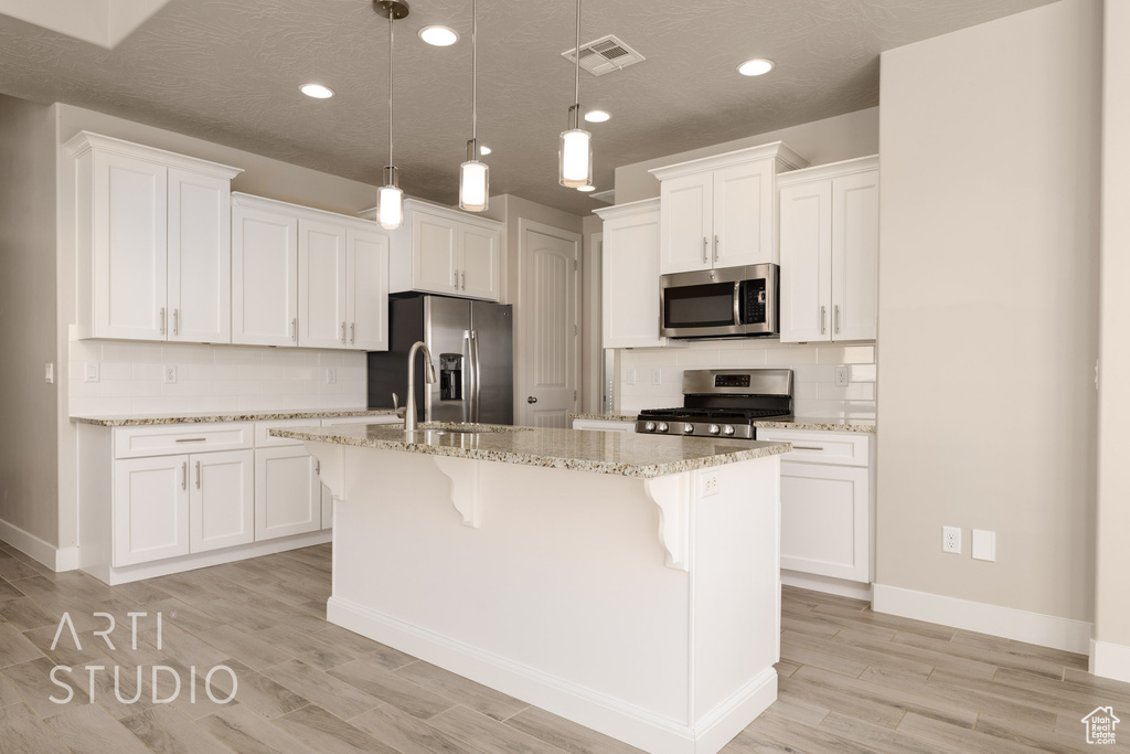 Kitchen featuring an island with sink, appliances with stainless steel finishes, sink, and white cabinetry